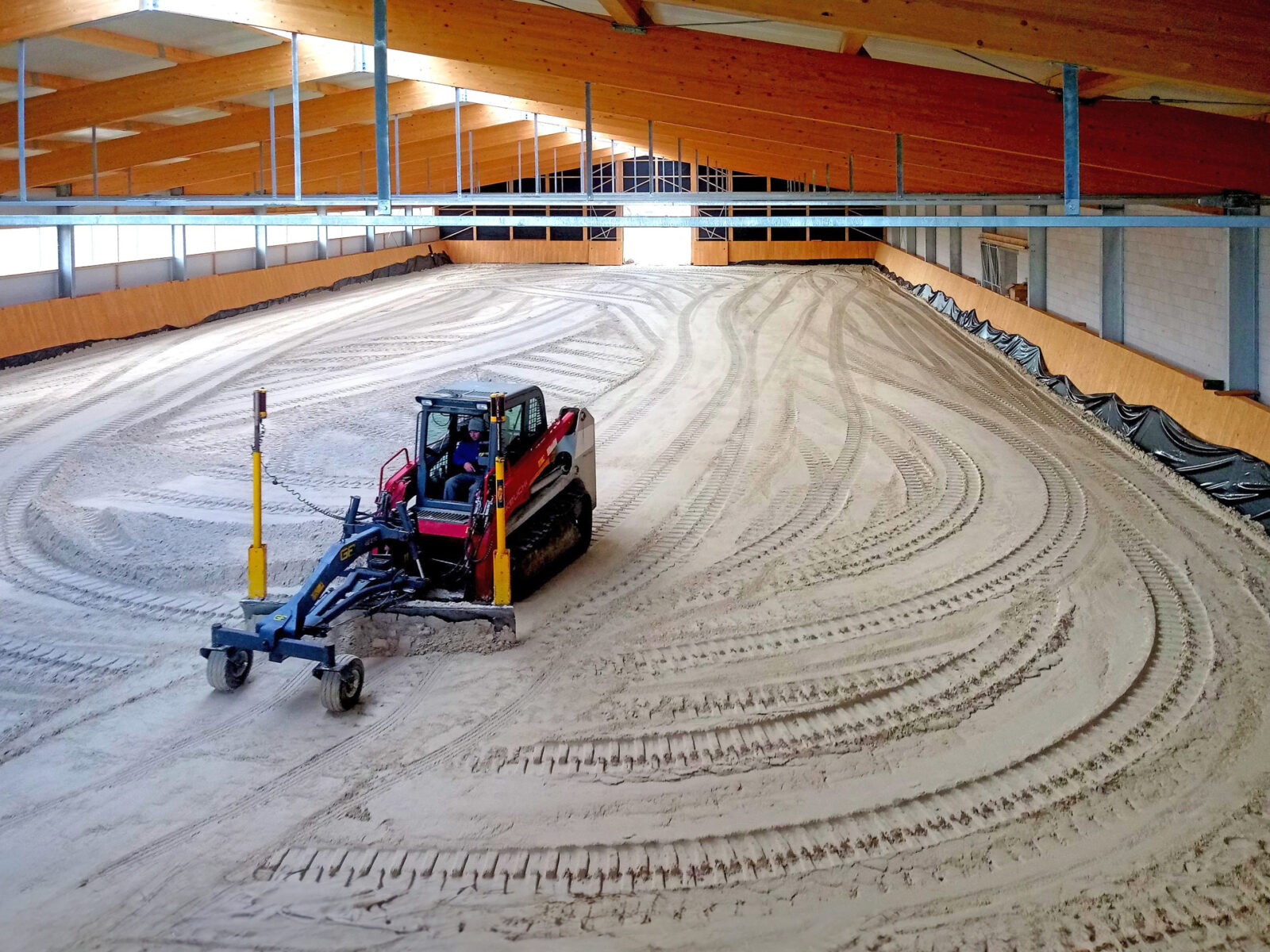 Indoor equestrian arena construction site – Dammann team building riding surface