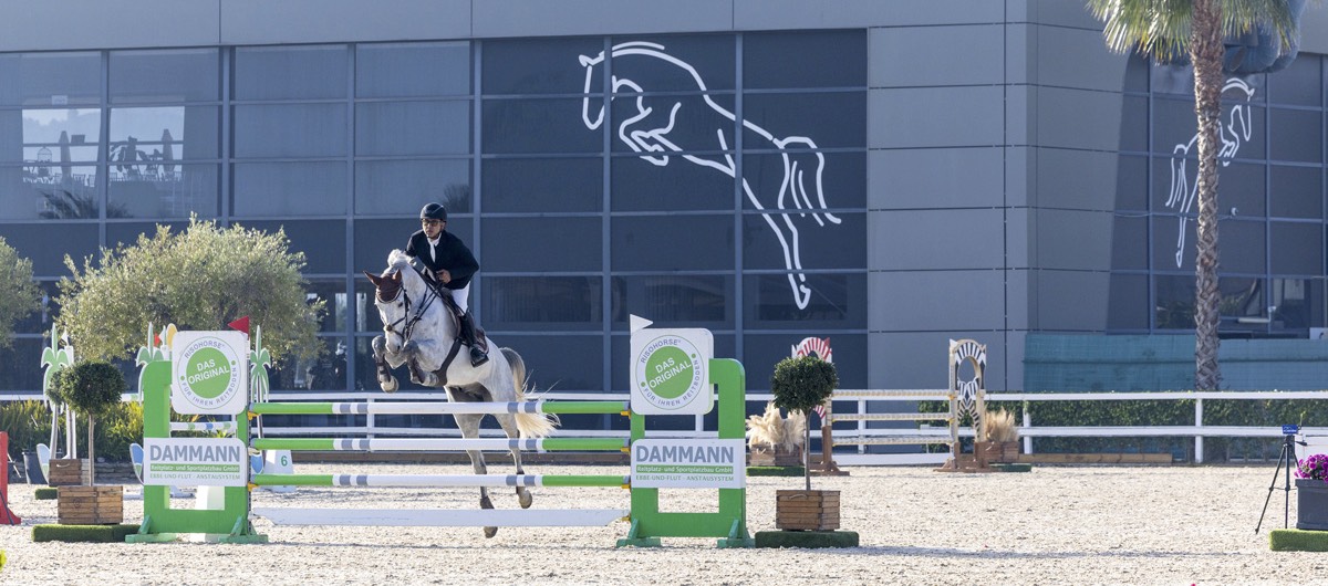 Jinete de salto ecuestre en competición sobre pista Risohorse® de flujo y reflujo